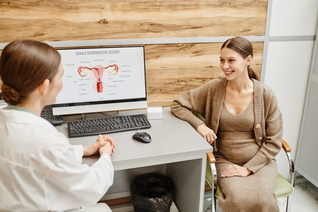Gynécologue échangeant avec une patiente enceinte devant un schéma de l'appareil reproducteur, première consultation au cabinet de gynécologie à Cannes.