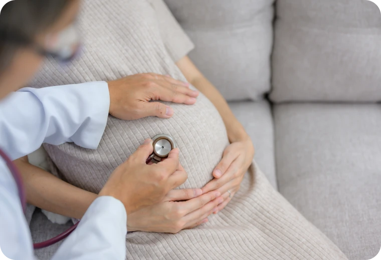 Médecin auscultant le ventre d'une femme enceinte au stéthoscope pour le suivi de grossesse